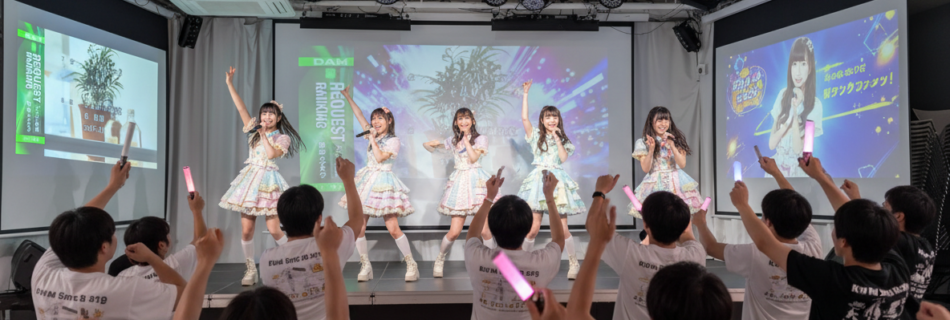 アイドル5人女性 男性多めの客がステージをスタンディングで向いて応援している 背景はなし